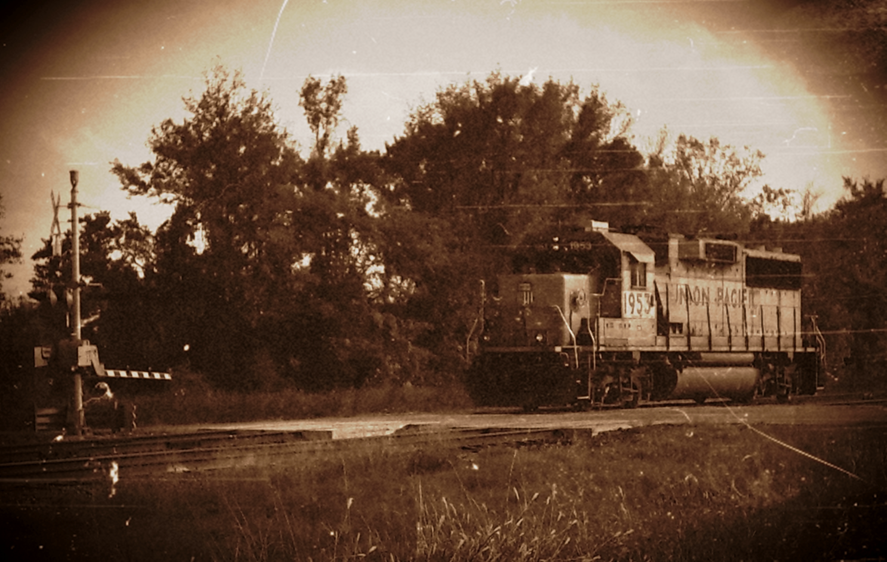A train on a railroad track coming up on a road crossing